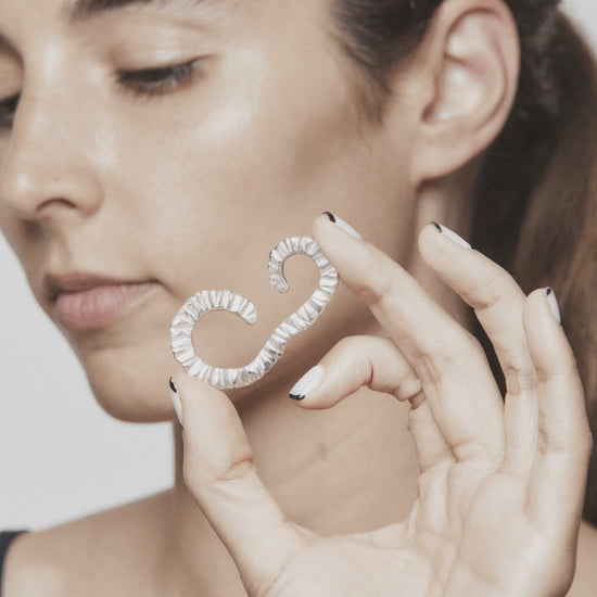 Stop motion showing how to wear the Flowing Upside Down ear cuff by AROE – silver sculptural jewelry flowing around the ear with elegant movement - Unique handcrafted silver ear cuff – statement jewellery by AROE.