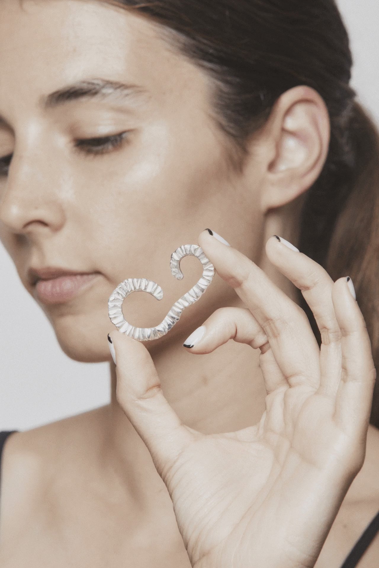 Stop motion showing how to wear the Flowing Upside Down ear cuff by AROE – silver sculptural jewelry flowing around the ear with elegant movement - Unique handcrafted silver ear cuff – statement jewellery by AROE.