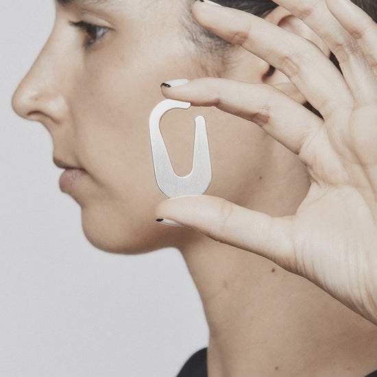 Unmarked Appeal earcuff in stop motion – showing a quiet ritual of adornment with a silver design that subtly completes the ear form BY AROE
